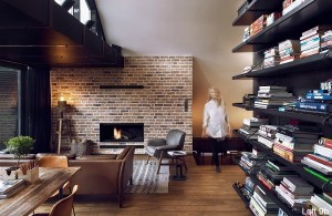 attic-apartment-with-custom-furniture-apartment-living-room-wooden-table-and-dark-bookshelf-brown-sofa-brick-fireplace