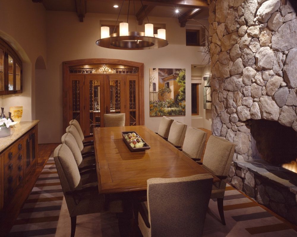 long rectangular wooden dining table with beige upholstered chairs and big stone fireplace