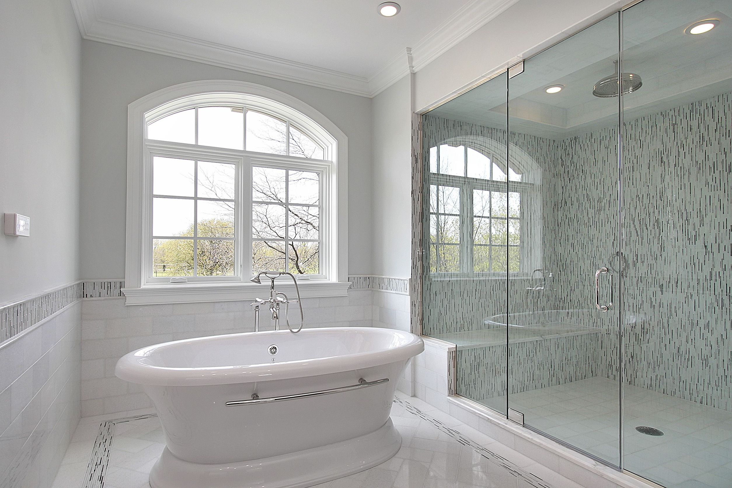 simple layout bathroom remodel with large arched window and white porcelain tub